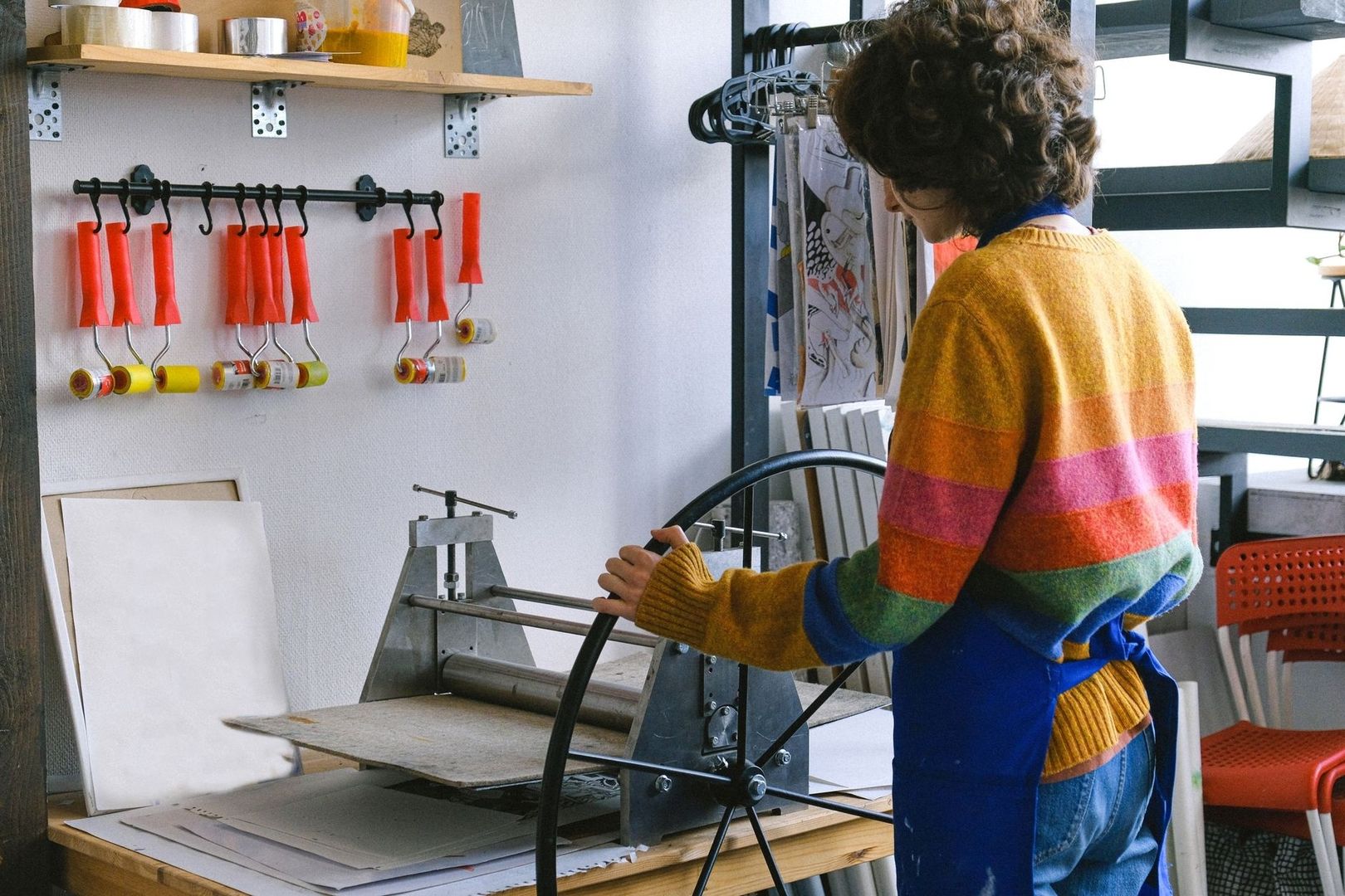 Grafische kunstenaar werkt met een etspers en rollers in het atelier